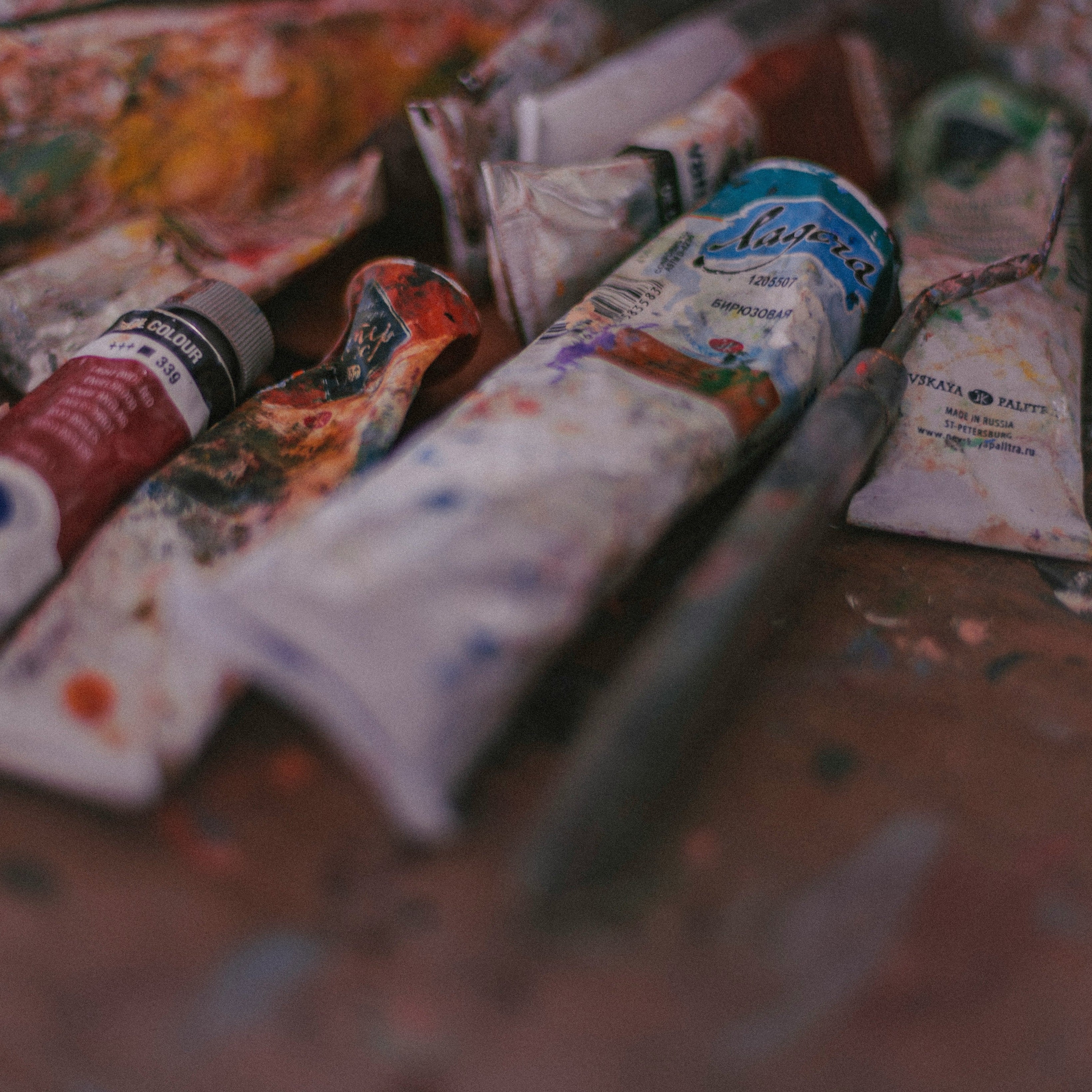 Art supplies including paint tubes and a palette on a table.